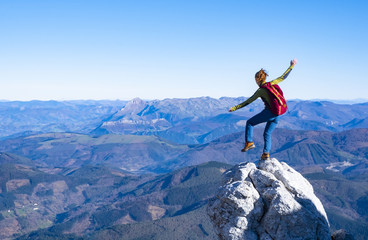 Happy celebrating winning success woman with arms raised in of having reached mountain top summit goal during hiking travel trek.