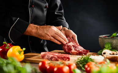 Chef seasoning a thick raw beef steak with spices