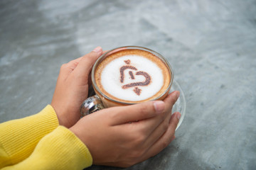 woman holding hot cup of coffee, with heart shape