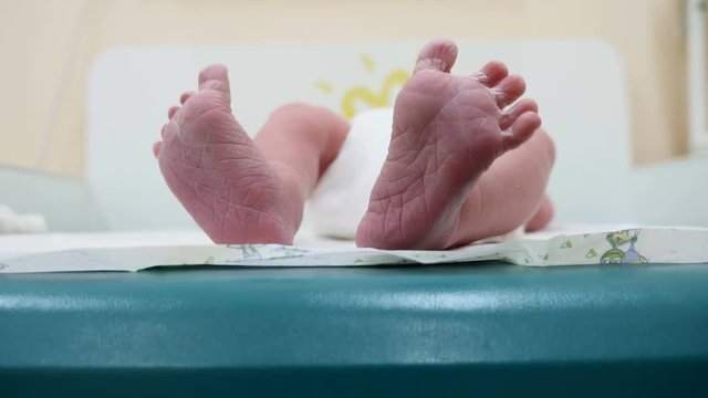 Newborn baby boy lying on back. Baby is kicking and stretching legs sreading fingers . Closeup shot on tiny soles of newborn feet. Baby sweetly bends his big toe and touches her feet together. 4k