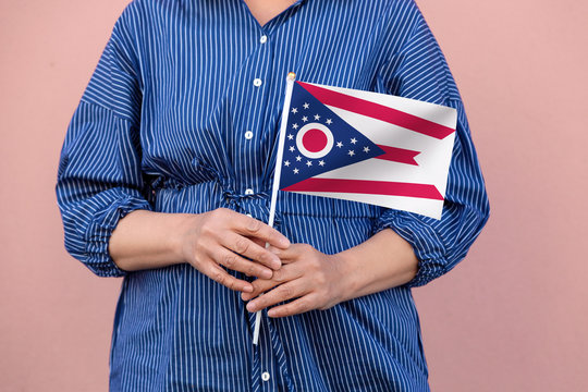 Ohio state flag. Close up of woman's hands holding Ohio flag.