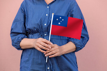 Samoa flag. Close up of a woman's hands holding Samoa flag.	