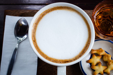 Fresh coffee with white cream, tea bread on a wooden tray