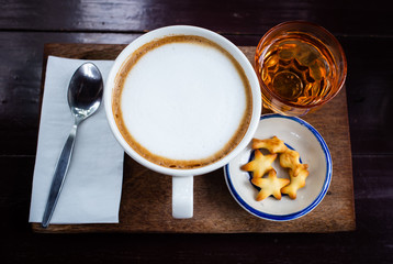 Fresh coffee with white cream, tea bread on a wooden tray