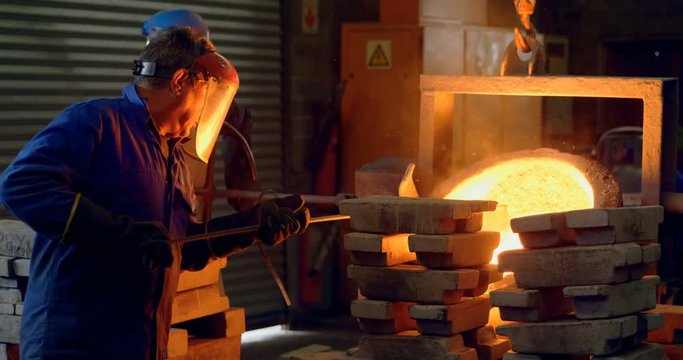 Male worker mixing molted metal in container at workshop 4k