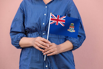 Cayman Islands flag. Close up of a woman's hands holding Cayman Islands flag.	