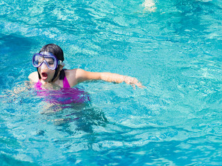 7 years girl wearing mask swimming in the pool. Happy holiday sunlight concept.