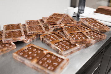 production and cooking concept - close up of chocolate cream in candy molds at confectionery shop