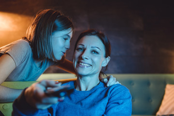 Mother watching TV while daughter saying good night