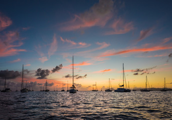 Fototapeta na wymiar Dark night view on sailing boat anchored on open sea with black silhouette of island