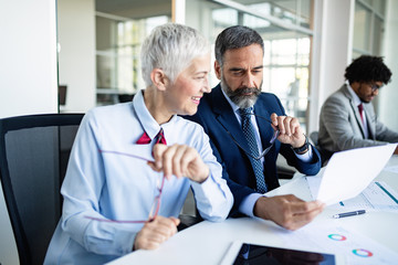 Happy mature businessman and businesswoman planning in office