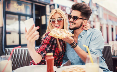 Couple sitting in the cafe and eating pizza. Consumerism, food, lifestyle concept