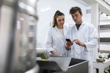 Young woman and young man using mobile in a factory