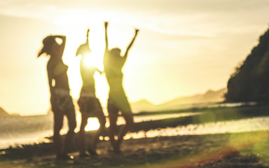 Blurred defocused silhouette of women travelers at sunset - Travel wanderlust concept with young girlfriends partying and dancing at the beach by El Nido Palawan - Warm contrasted sunshine filter