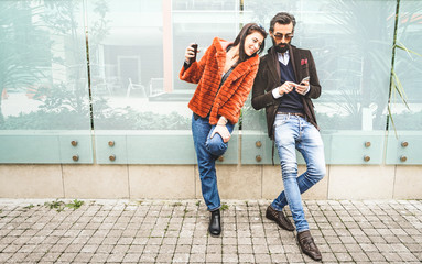 Happy hipster couple having fun with mobile smart phone at outdoors location - Friendship concept...