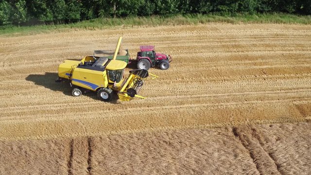Aerial of a yellow combine harvester in a beautiful golden wheat field as it harvests on a bright sunny day in bavaria germany