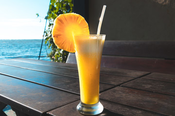 glass of pineapple juice with blue sky lake in background