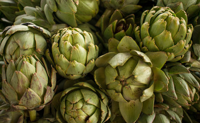 Obraz premium Close up of group fresh globe artichoke (Cynara cardunculus) at a farmers market. Healthy food. Organic background.