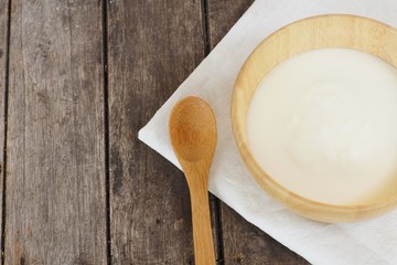 Plain organic yogurt in wooden bowl and wood spoon on wood texture background