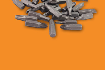 One heap of different interchangeable heads or bits for manual screwdriver for woodworking and metalworking on orange background with copy space for your text. Building or repair concept