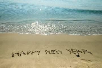 Happy New Year write on sand beach background