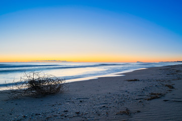 first light of day on a clear morning at the beach of Valencia. Magical bluish sunrise with orange glow background.