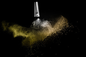 Cosmetic brush with golden cosmetic powder spreading for makeup artist and graphic design in black background, look like a luxury mood.