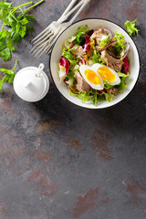 Diet food tuna salad with boiled egg, canned fish, onion and green lettuce top view