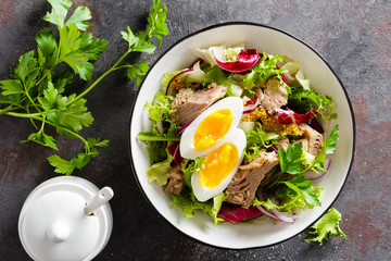 Diet food tuna salad with boiled egg, canned fish, onion and green lettuce top view