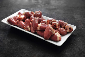 Serduszka na talerzu. Serca drobiowe na ciemnym  tle. © foodandcook
