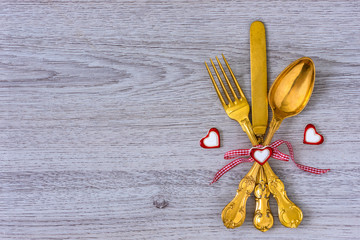 Essbesteck mit einer Schleife und Herzen auf einem Holztisch