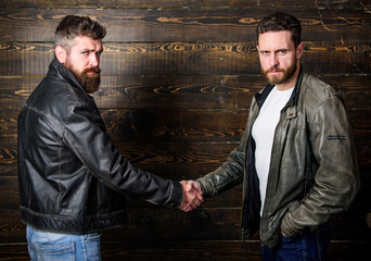 Male friendship concept. Brutal bearded men wear leather jackets shaking hands. Real men and...