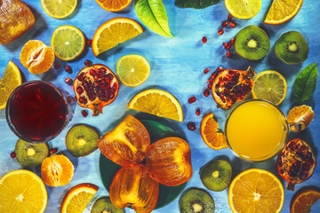 pomegranate and orange juice and citrus fruits on a blue background.