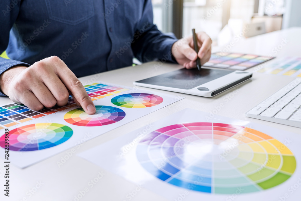 Poster male creative graphic designer working on color selection and color swatches, drawing on graphics ta