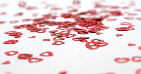 Red heart shaped confettis falling down on white surface 4k - Powered by Adobe
