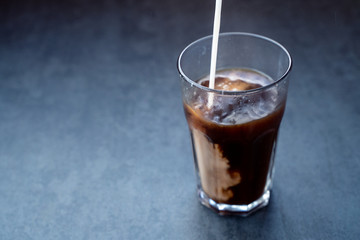 Pouring milk into coffee latte in the glass on a dark gray stone table, copy space.