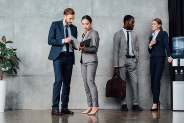 focused multiethnic businesspeople in formal wear talking in waiting hall