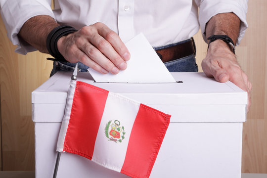 A Peruvian Citizen Inserting A Ballot Into A Ballot Box. Peru Flag In Front Of It