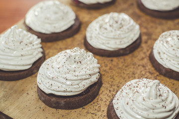 Chocolate cakes with egg white cream on the wooden board. Sweet and tasty homemade food.