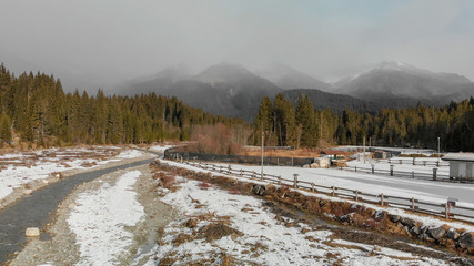 Aerial panoramic view of mountain valley in winter with snow, forest and river