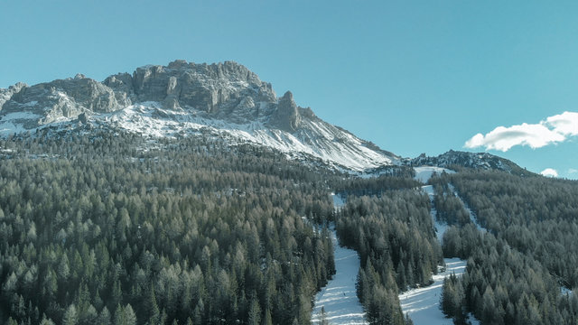 Aerial view of dolomites alps in winter with forest and lake.