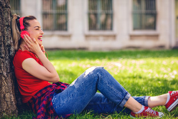 smiling girl listening to music in city park.