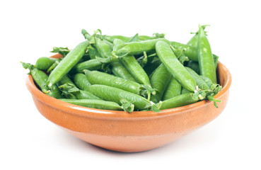 green peas in pods.  in a clay plate on a white background
