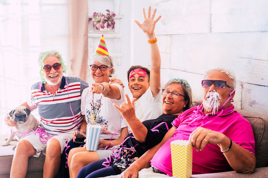 Having Fun For People With No Age Limits At Home - Grandfathers And Grandson All Together In Carnival Indoor Party Celebration - Crazy Men And Women With Old Dog Pug Sitting On The Couch