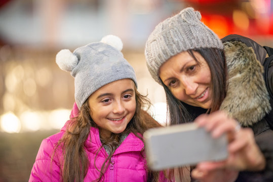 Young girl with mother happy in the city at night making selfie