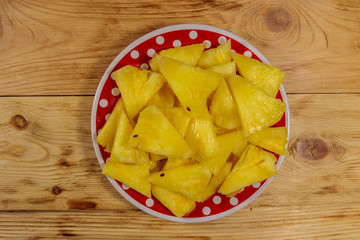 Pieces of pineapple in a plate on wooden table. Top view