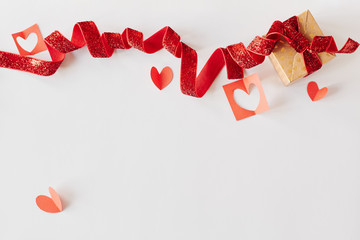 Cardboard gift box with red ribbon and red paper hearts on white background. Valentine's day, love, holiday present concept
