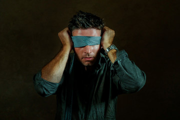 young lost and confused man blindfolded with necktie playing internet trend dangerous viral...