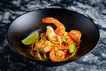 Stir fry noodles with vegetables and seafoods in black bowl