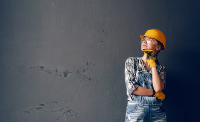 a strong-willed woman in a construction helmet, mittens, goggles and overalls is engaged in repair...